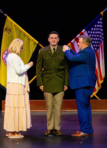 William Piskutz pins the second lieutenant bars on his son, Gavin, with his mother, Cheryl, by his side.